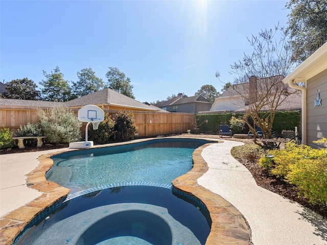 view of swimming pool with a fenced backyard and a pool with connected hot tub