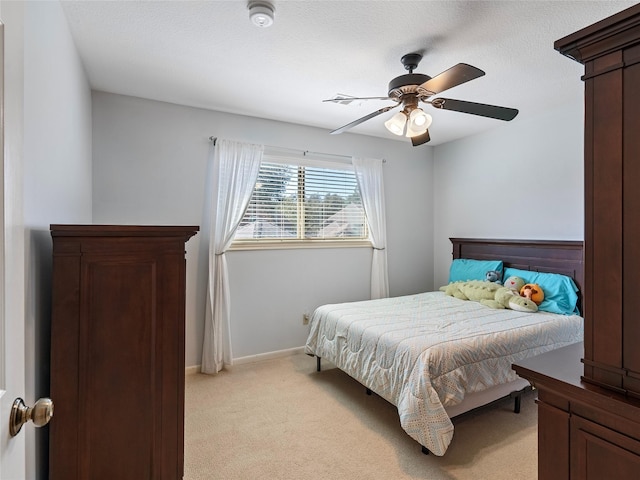 bedroom featuring baseboards, a textured ceiling, a ceiling fan, and light colored carpet