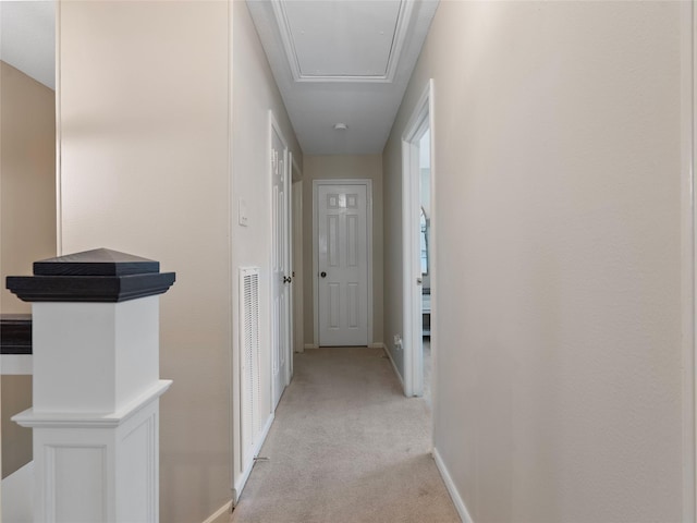 corridor featuring light carpet, attic access, and baseboards