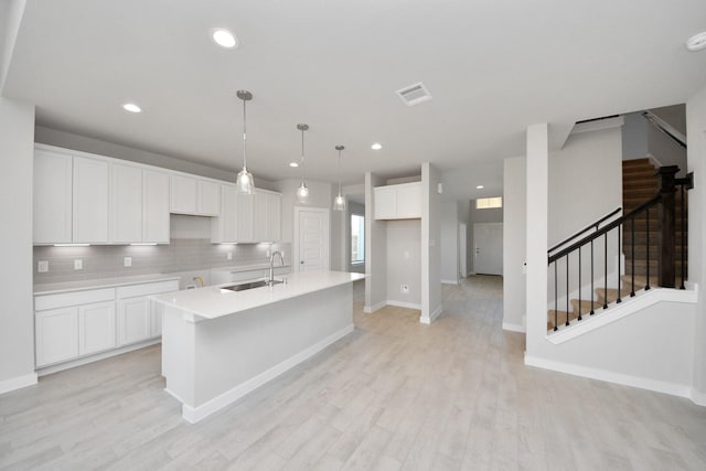 14811 Surfbird Ln, Houston, TX 77049 - kitchen featuring visible vents, an island with sink, light wood-style floors, white cabinetry, and a sink