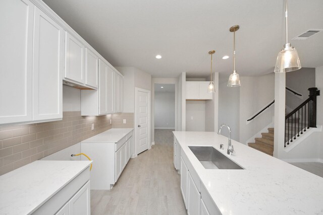 14811 Surfbird Ln, Houston, TX 77049 - kitchen with light wood finished floors, decorative backsplash, white cabinets, and a sink
