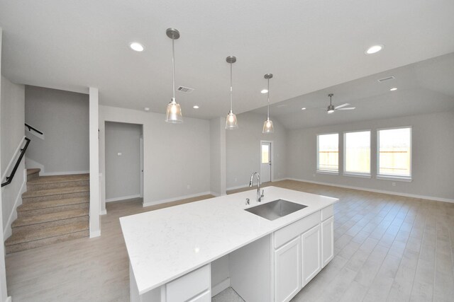 14811 Surfbird Ln, Houston, TX 77049 - kitchen with light wood finished floors, visible vents, open floor plan, white cabinets, and a sink