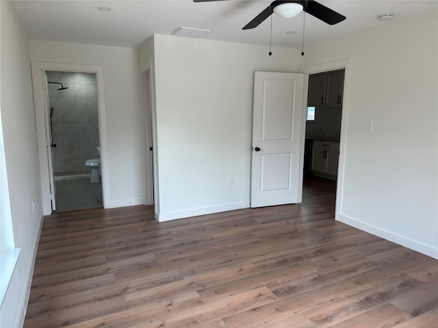 unfurnished bedroom featuring ensuite bathroom, ceiling fan, wood finished floors, visible vents, and baseboards