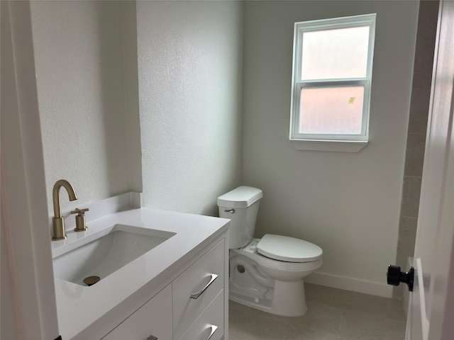 bathroom with tile patterned flooring, baseboards, vanity, and toilet