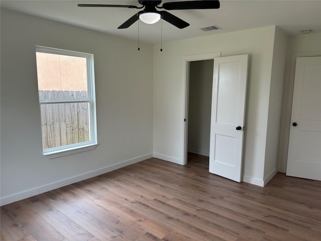 unfurnished bedroom featuring baseboards, visible vents, ceiling fan, and wood finished floors