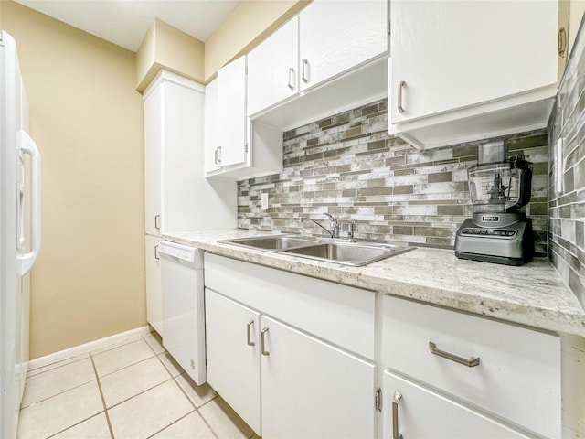 kitchen featuring white appliances, light tile patterned floors, white cabinets, decorative backsplash, and a sink