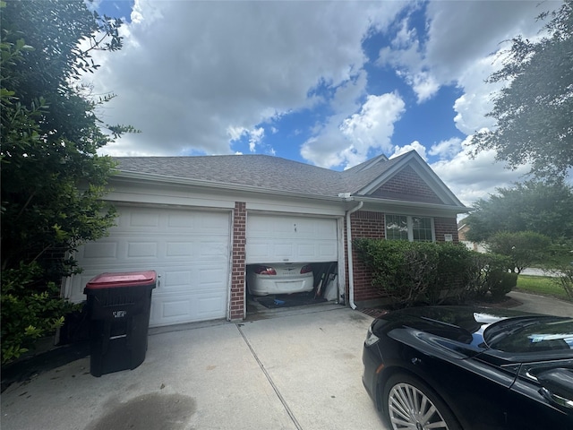 view of front of property featuring brick siding, driveway, an attached garage, and roof with shingles