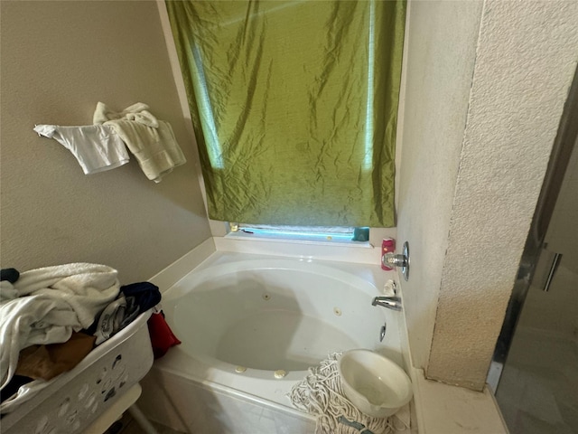 bathroom featuring a textured wall and a whirlpool tub