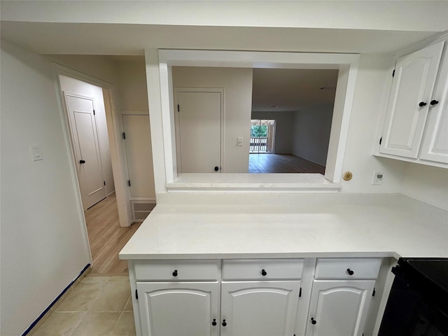 kitchen with light countertops, white cabinets, black range with electric stovetop, and light tile patterned floors