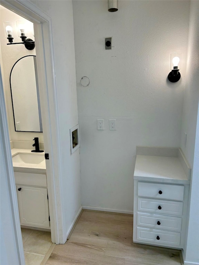 bathroom with wood finished floors, vanity, and baseboards