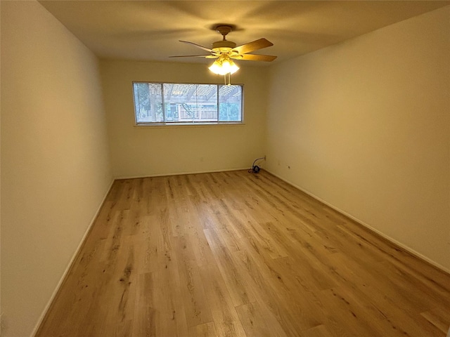 spare room with light wood-type flooring, ceiling fan, and baseboards