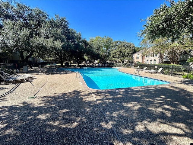 community pool with a patio area and fence