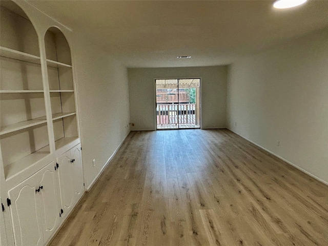 empty room featuring visible vents, light wood-style flooring, and built in features