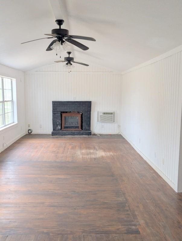 unfurnished living room with vaulted ceiling, a fireplace with raised hearth, wood finished floors, and a wall mounted AC