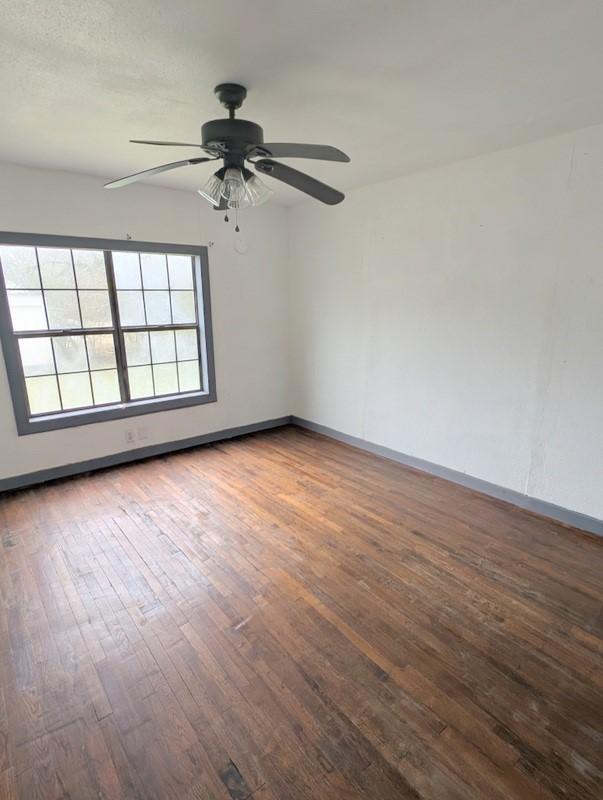 spare room with a ceiling fan, baseboards, and hardwood / wood-style flooring