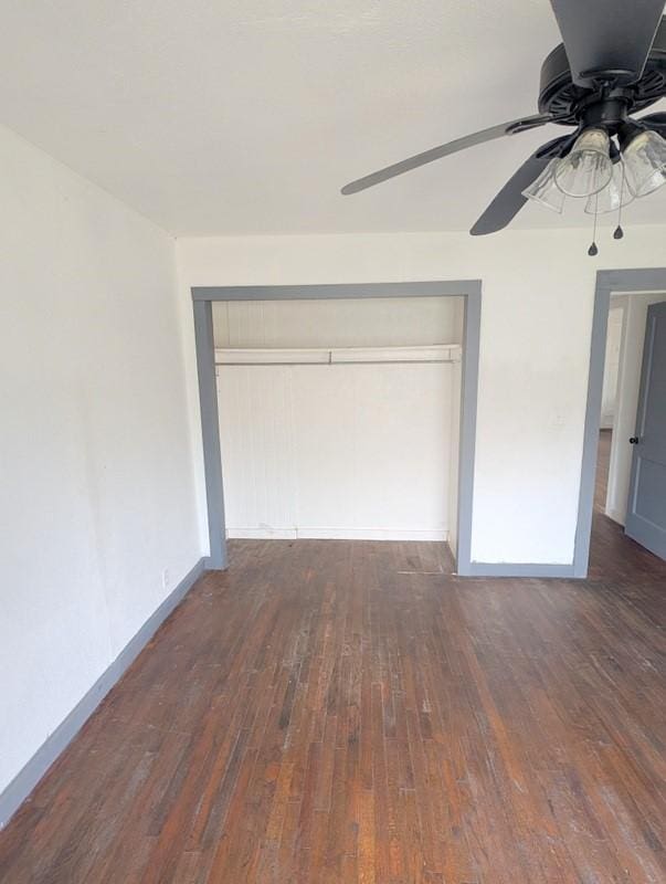 unfurnished bedroom with baseboards, a closet, hardwood / wood-style flooring, and a ceiling fan