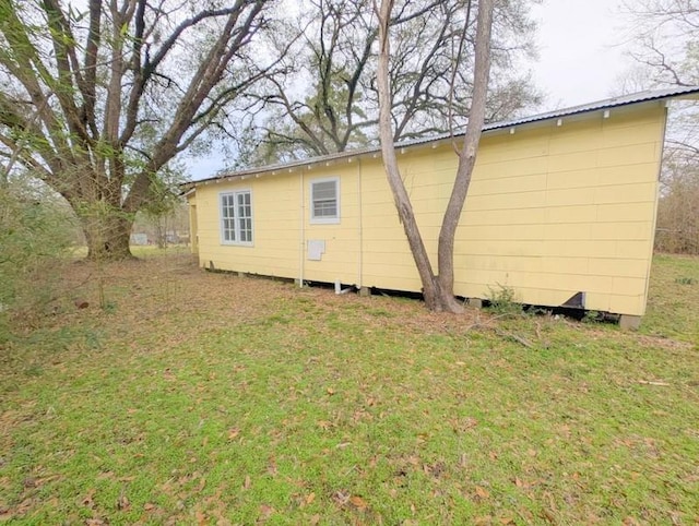 view of property exterior with a yard and metal roof