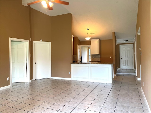 kitchen with light tile patterned floors, baseboards, white cabinets, visible vents, and vaulted ceiling