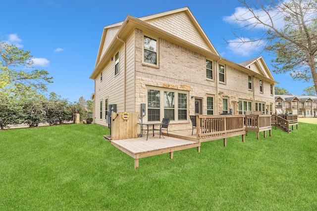 back of house with brick siding, a wooden deck, and a yard