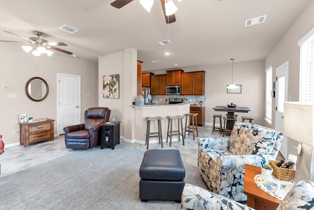 living room with visible vents, light carpet, and ceiling fan