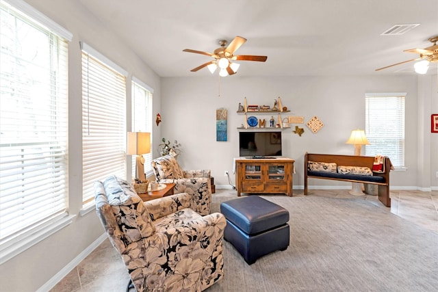 living room featuring visible vents, carpet flooring, baseboards, and ceiling fan