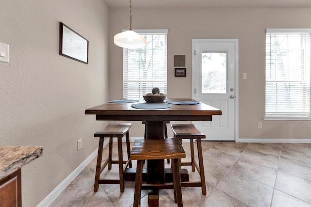 dining area with light tile patterned floors, a healthy amount of sunlight, and baseboards