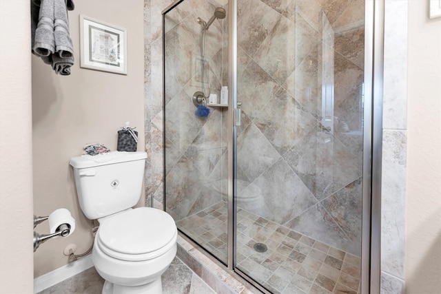 bathroom with a shower stall, toilet, and baseboards