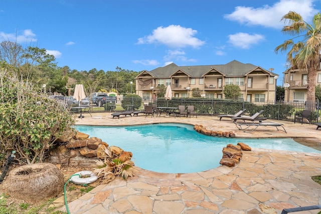 community pool with a patio area and fence