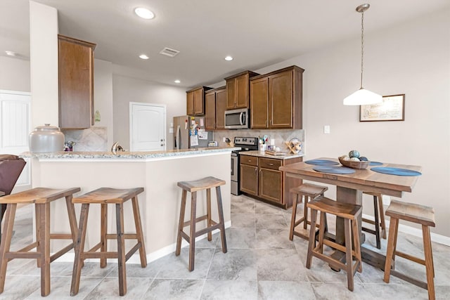 kitchen with a breakfast bar area, visible vents, a peninsula, stainless steel appliances, and tasteful backsplash