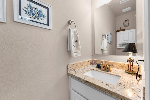 bathroom with vanity and a textured wall