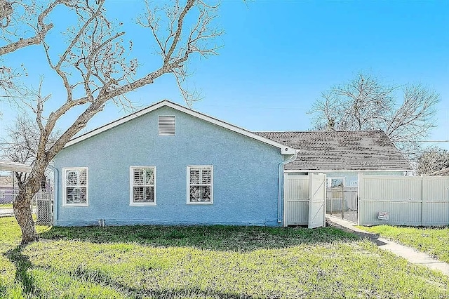 back of property featuring a lawn, fence, and stucco siding