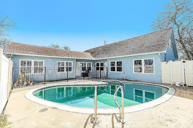 view of swimming pool with a patio area, a pool with connected hot tub, and fence