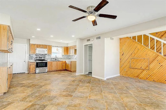 kitchen with white microwave, a sink, stainless steel range with electric cooktop, light countertops, and decorative backsplash