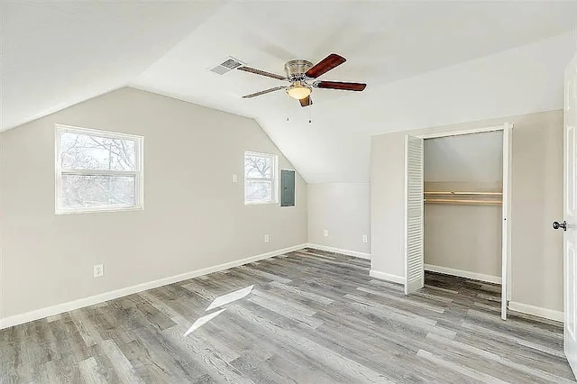 additional living space featuring ceiling fan, wood finished floors, baseboards, vaulted ceiling, and electric panel