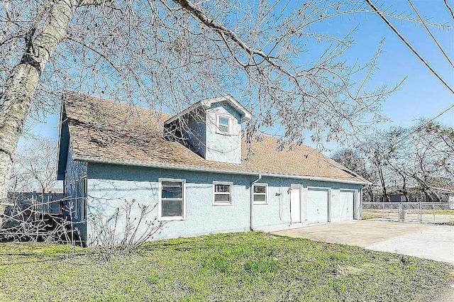 exterior space with concrete driveway, a lawn, and fence