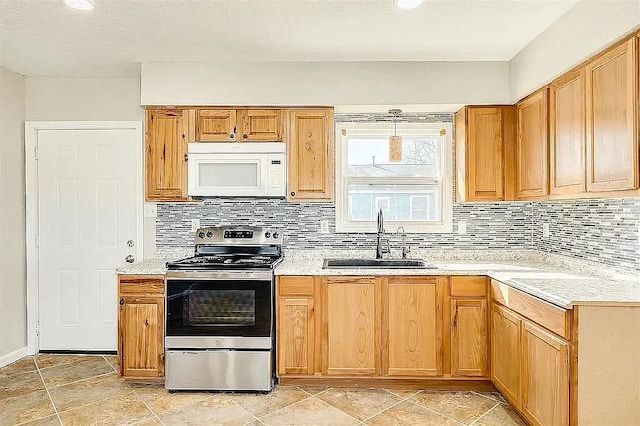 kitchen with white microwave, tasteful backsplash, a sink, and stainless steel range with electric cooktop