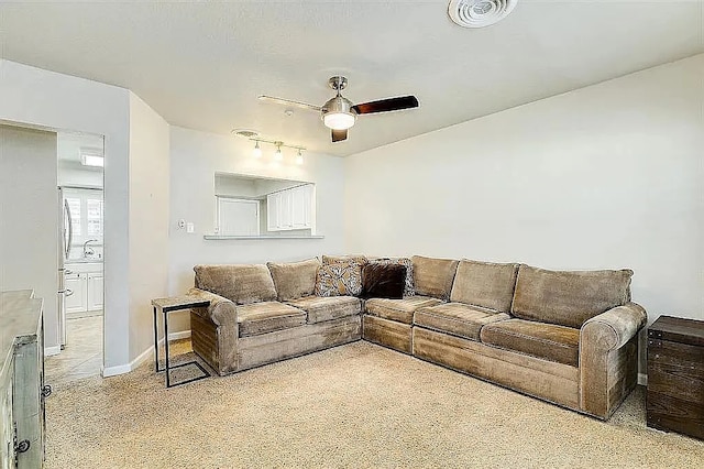 living area with ceiling fan, baseboards, visible vents, and light colored carpet