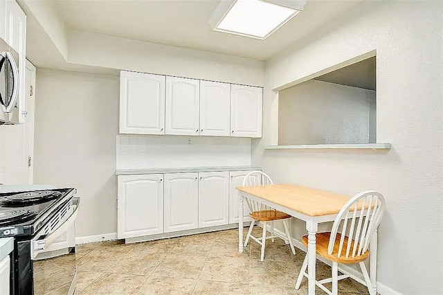 kitchen featuring black / electric stove, light tile patterned flooring, baseboards, white cabinets, and stainless steel microwave