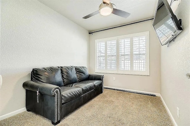 living room featuring carpet, baseboards, a ceiling fan, and a textured wall