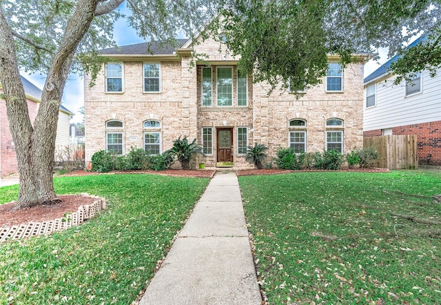 view of front of home featuring brick siding, a front yard, and fence