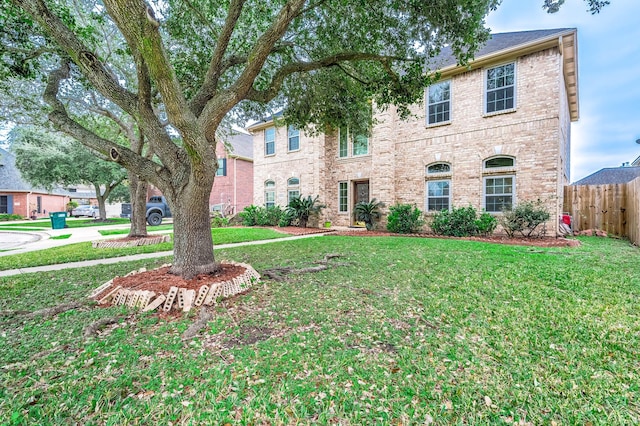 view of front facade with fence, a front lawn, and brick siding