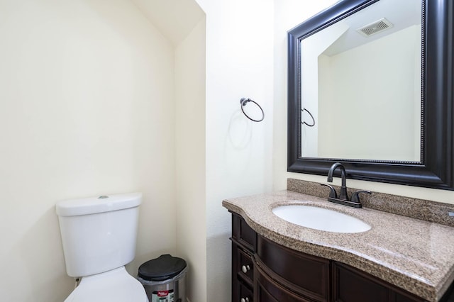 bathroom with toilet, vanity, and visible vents