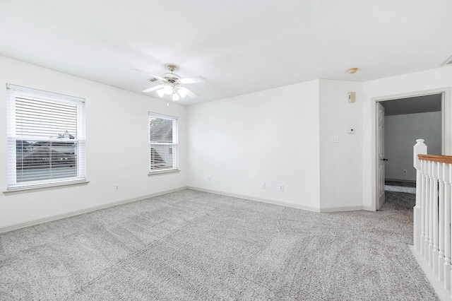 empty room with light carpet, a ceiling fan, and baseboards