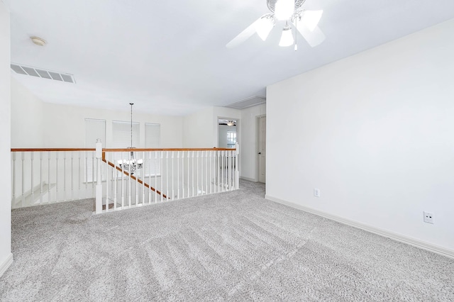 empty room with baseboards, visible vents, carpet flooring, and ceiling fan with notable chandelier