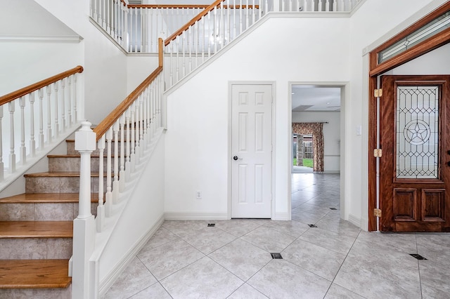 foyer with stairs, a high ceiling, tile patterned floors, and baseboards