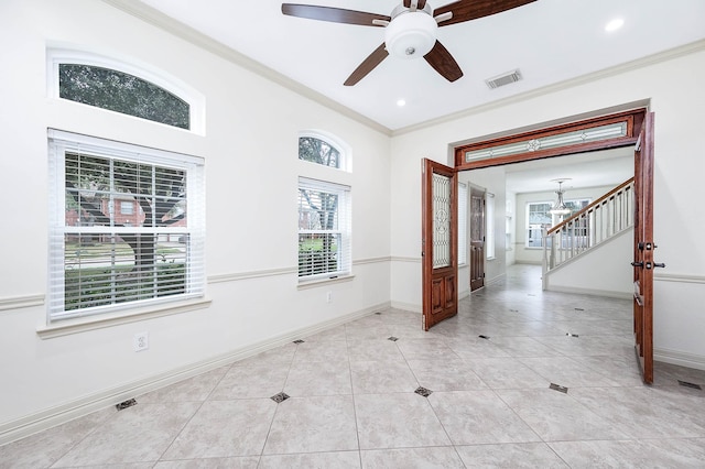 empty room with light tile patterned floors, baseboards, visible vents, and crown molding