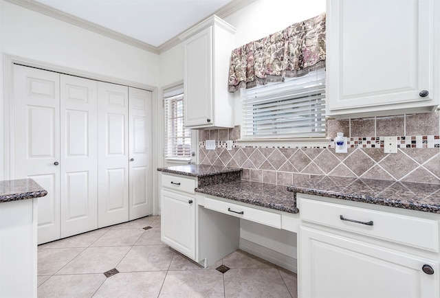 kitchen with white cabinets, decorative backsplash, ornamental molding, dark stone countertops, and light tile patterned flooring