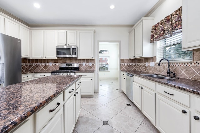 kitchen with light tile patterned flooring, a sink, ornamental molding, appliances with stainless steel finishes, and tasteful backsplash