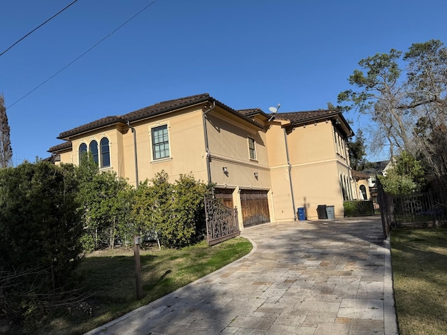 11117 Beinhorn Rd, Houston, TX 77024 - view of side of property with decorative driveway, stucco siding, a gate, and fence