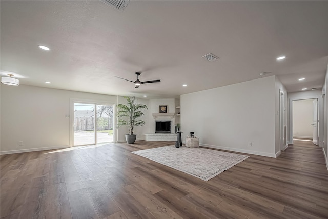 unfurnished living room with baseboards, visible vents, ceiling fan, wood finished floors, and a fireplace